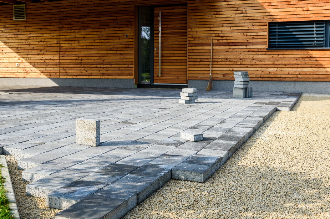 Laying gray concrete paving slabs in house courtyard driveway patio.