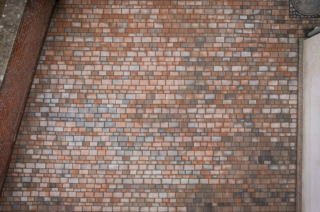 Eine gleichmäßige Backsteinwand mit variierenden Rot- und Grautönen aus der Vogelperspektive