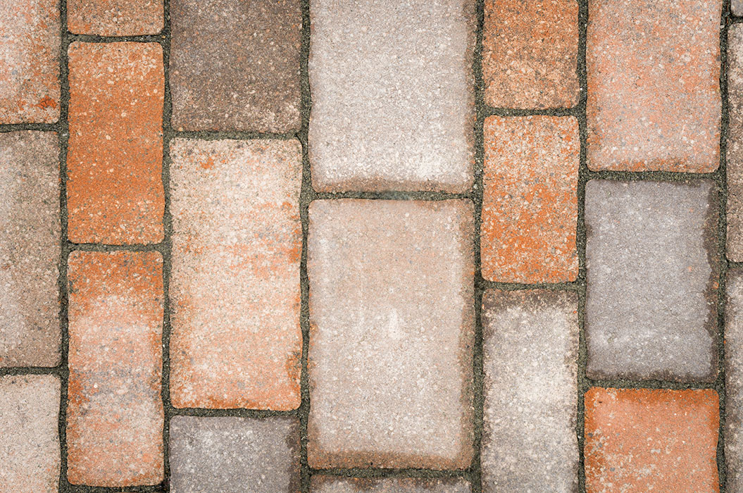 Rötlich und grau gefärbte, rechteckige Pflastersteine in abwechslungsreicher Anordnung