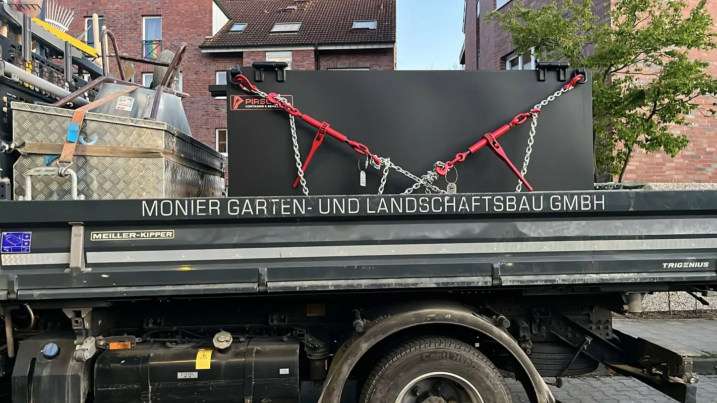 Schwarzer Container mit roten Gurten auf grauem Lkw in der Stadt
